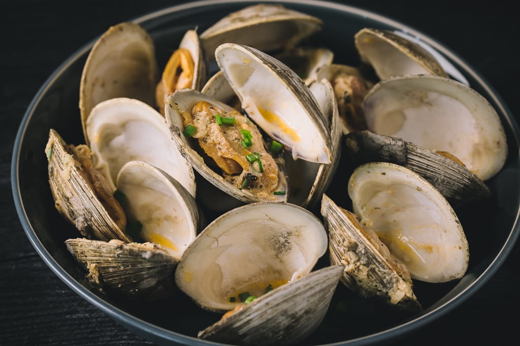 Grilled clams in a large serving bowl.