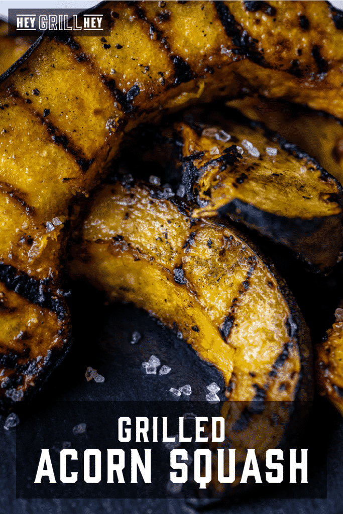 Grilled acorn squash spears stacked on a serving dish with text overlay - Grilled Acorn Squash.