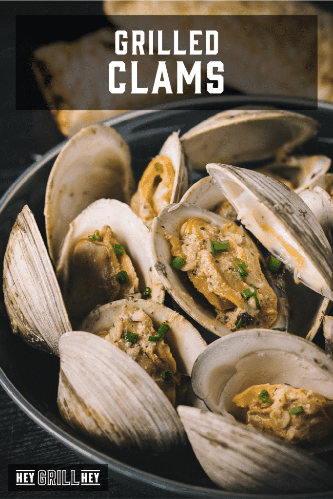 Grilled clams in a large serving bowl with text overlay - Grilled Clams.