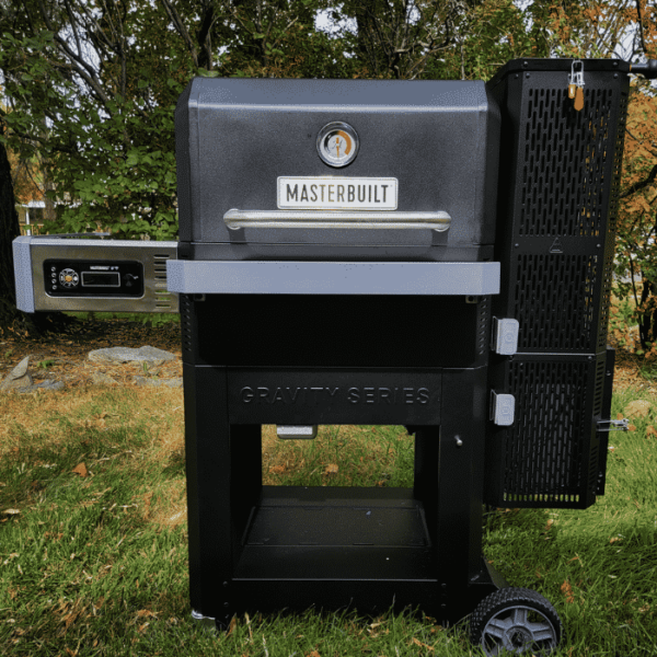 Front view of a Masterbuilt Gravity Series smoker on a lawn.