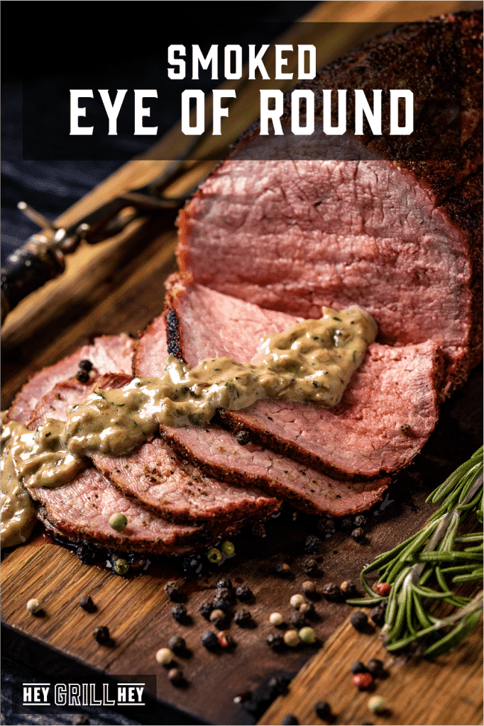 Sliced smoked eye of round drizzled with whiskey cream sauce on a wooden cutting board with text overlay - Smoked Eye of Round.