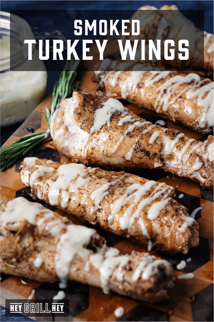 Smoked turkey wings drizzled with gravy dipping sauce on a wooden serving board with text overlay - Smoked Turkey Wings.