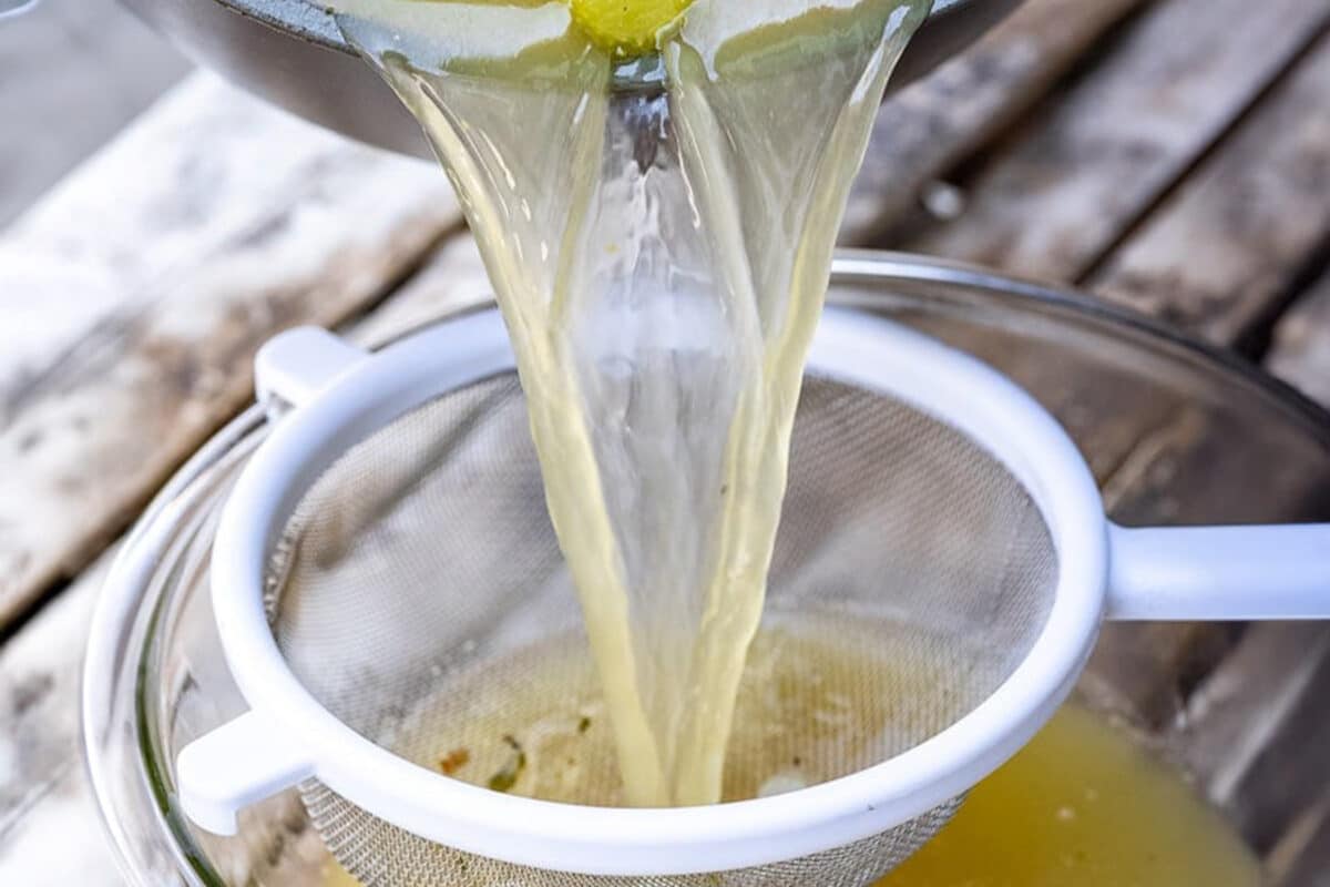 Turkey stock being strained into a bowl.