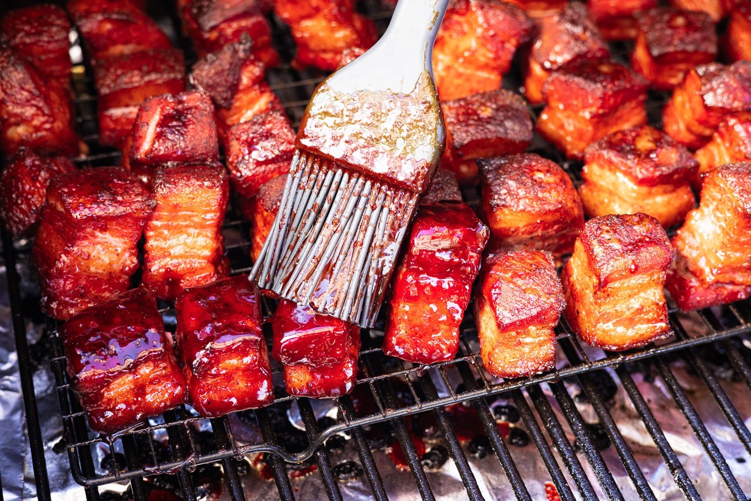 Char siu glaze being brushed onto smoked pork belly cubes.