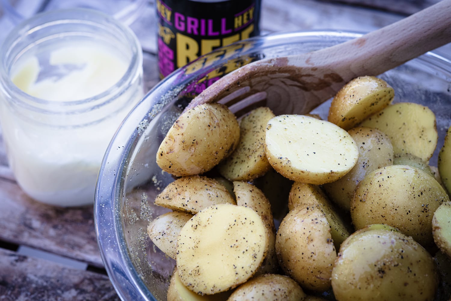 Baby potatoes being seasoned with Hey Grill Hey Beef Rub in a glass bowl.
