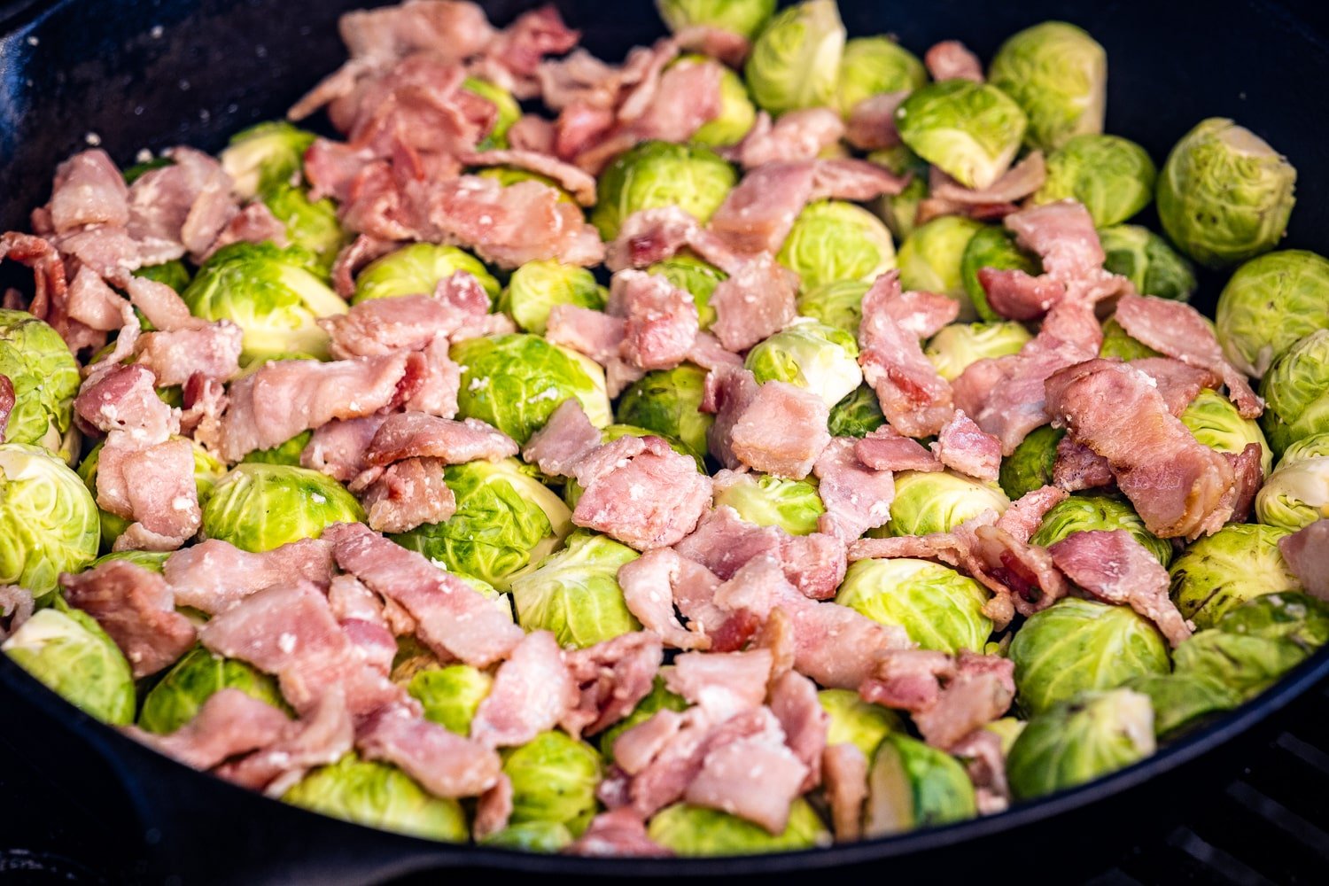 Brussels sprouts and chopped bacon in a cast iron skillet.