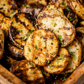 Seasoned and grilled baby potatoes stacked in a rectangular serving dish.