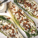 Three grilled romaine hearts topped with ranch dressing and bacon bits.