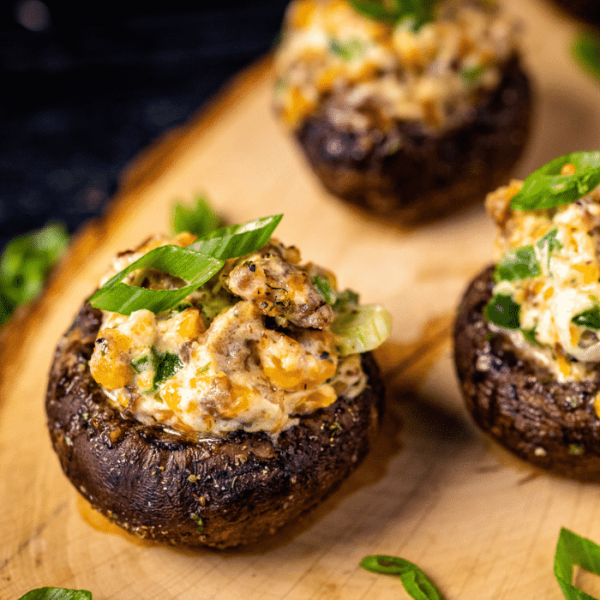 Grilled stuffed mushrooms on a wooden serving board.
