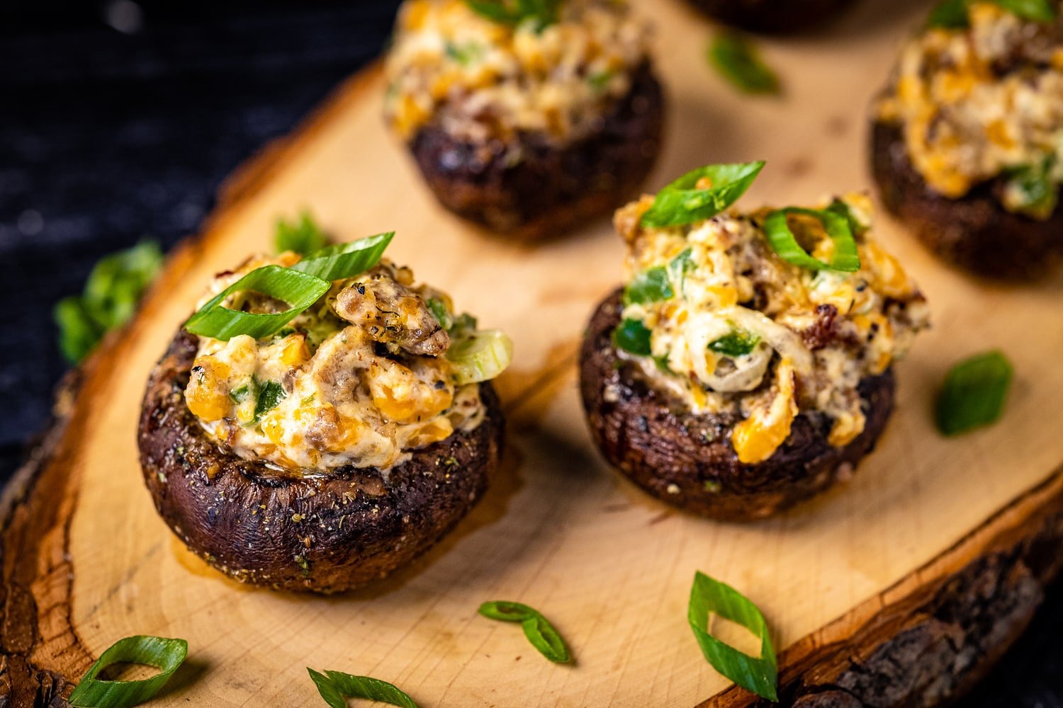 Grilled stuffed mushrooms on a wooden serving board.