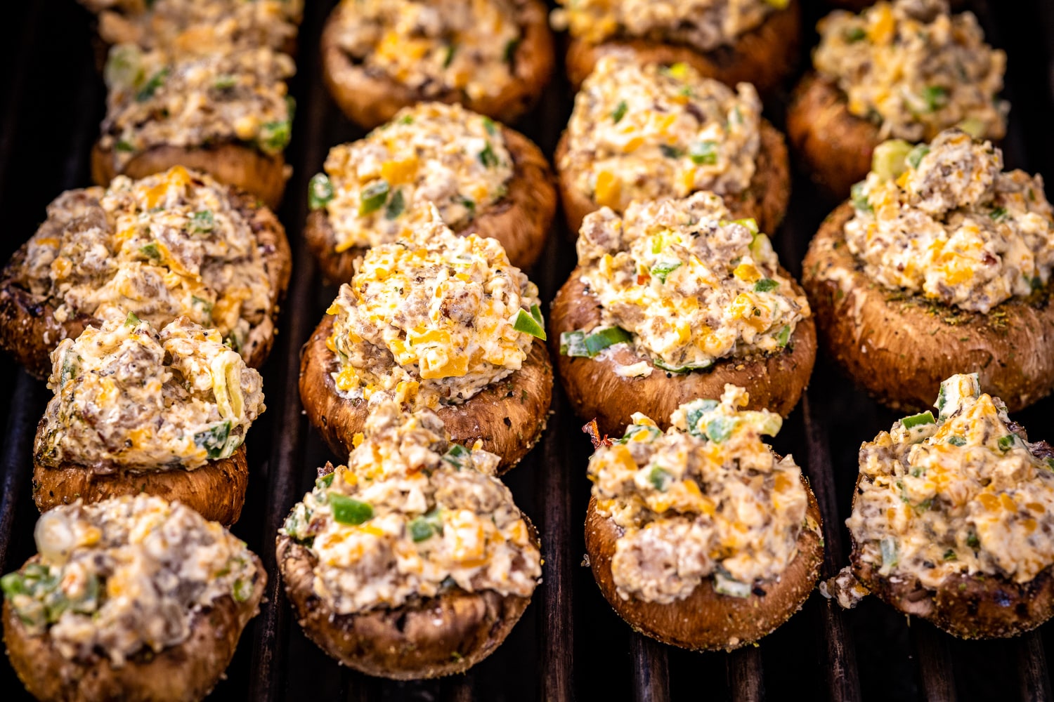 Stuffed mushrooms on the grill grates of a gas grill.