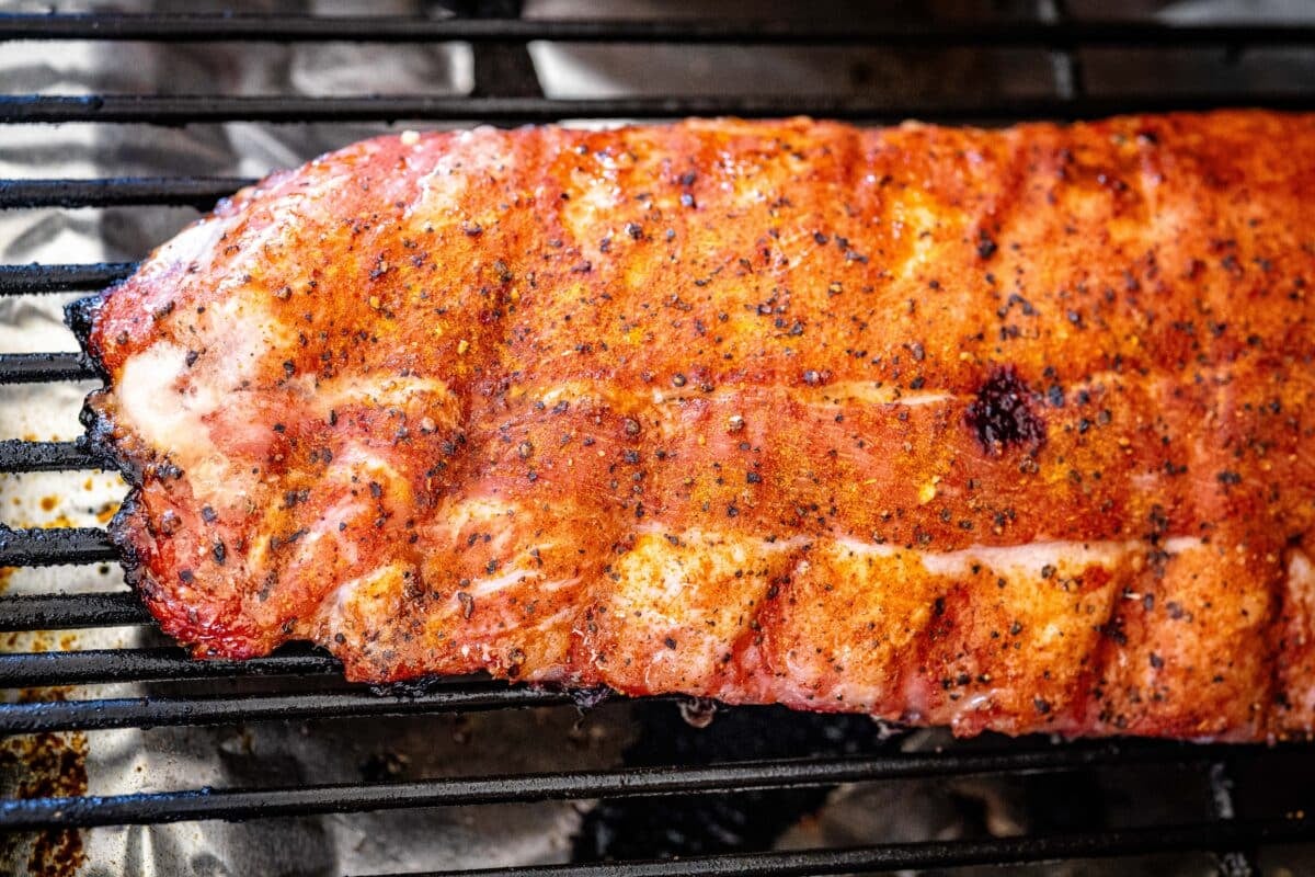 Seasoned ribs on the grates of a smoker.