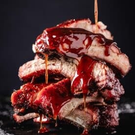 Sauce drizzling onto a stack of pork ribs.