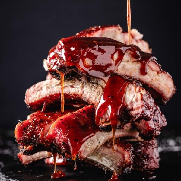 Sauce drizzling onto a stack of pork ribs.