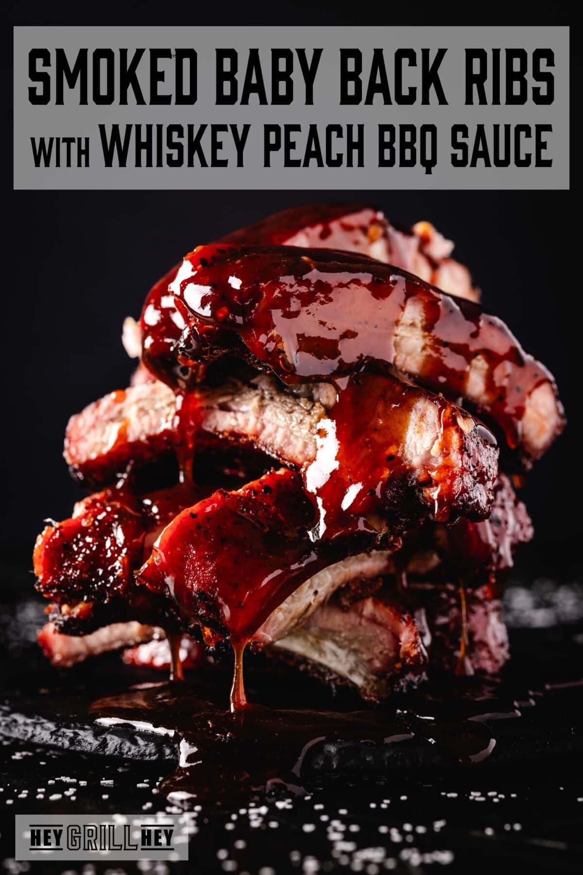 A stack of smoked and sauced baby back ribs. The text overlay reads "Smoked Baby Back Ribs with Whiskey Peach BBQ Sauce" at the top, and "Hey Grill Hey" at the bottom.