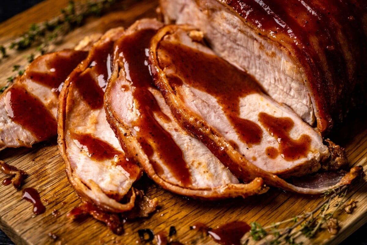 Sliced bacon wrapped smoked pork loin drizzled with Whiskey Peach BBQ Sauce.