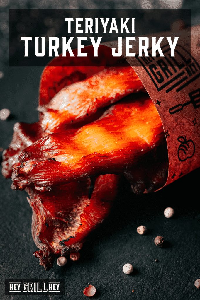 Slices of teriyaki turkey jerky wrapped in Hey Grill Hey branded peach butcher paper with text overlay - Teriyaki Turkey Jerky.