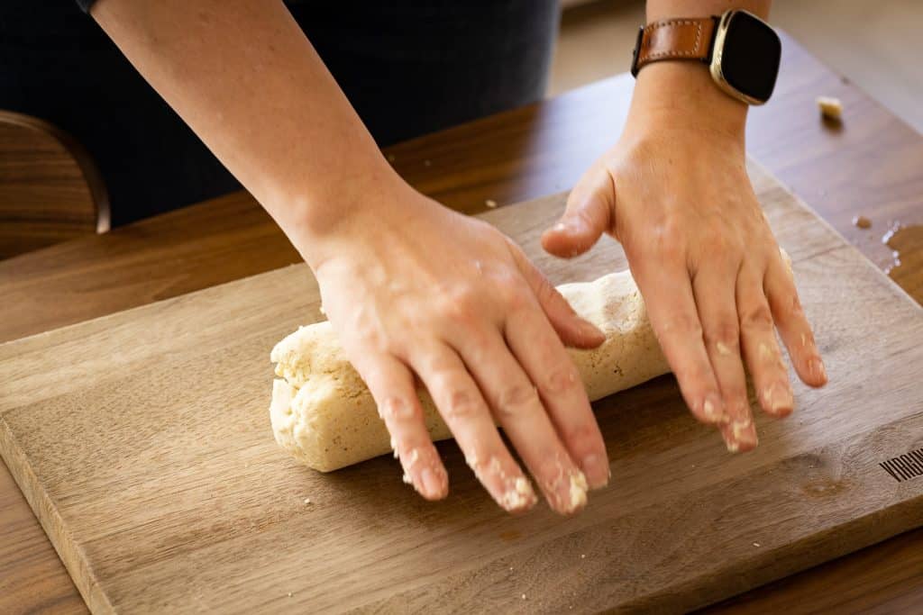 Dough being rolled into a cylinder.
