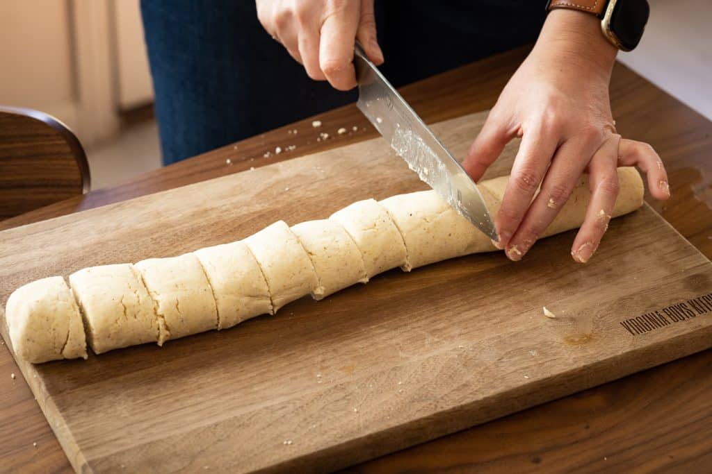 Knife slicing rolled dough into even pieces.