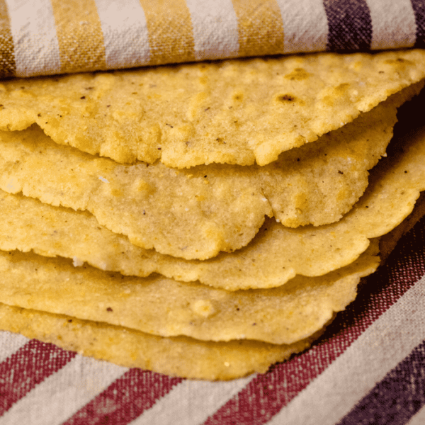 Stack of grilled corn tortillas on a kitchen towel.