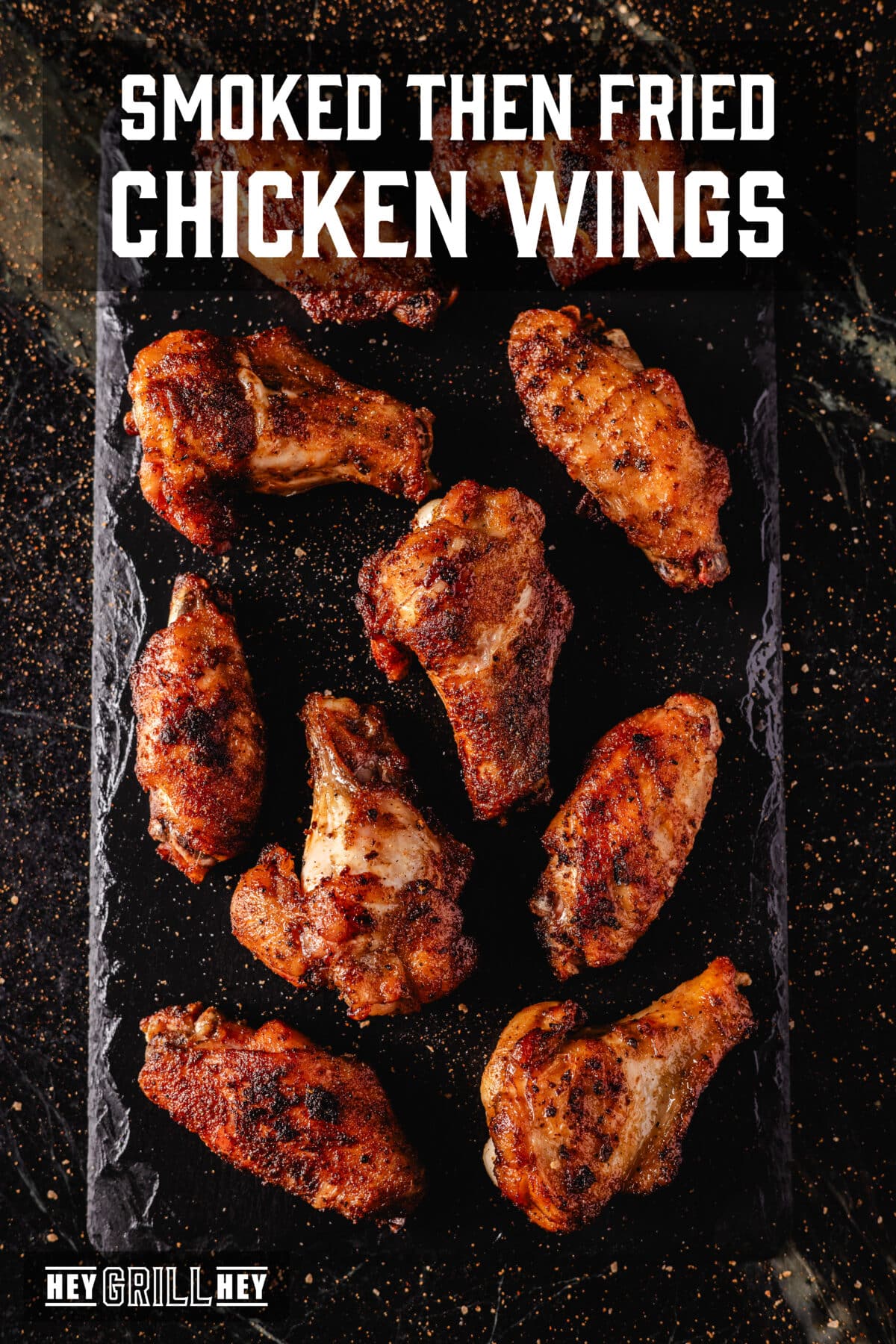 An overhead shot of a black platter topped with fried chicken wings. The text overlay reads "Smoked Then Fried Chicken Wings" at the top, and "Hey Grill Hey" at the bottom.