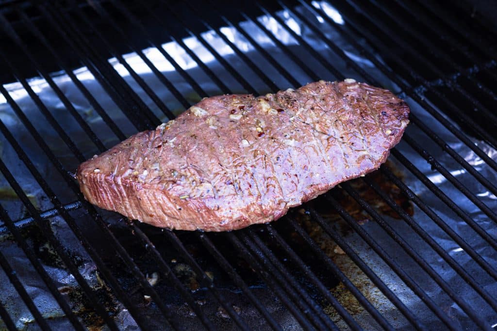 London broil on the grill grates of a smoker.