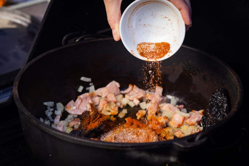 Seasoning being poured into a cast iron skillet.