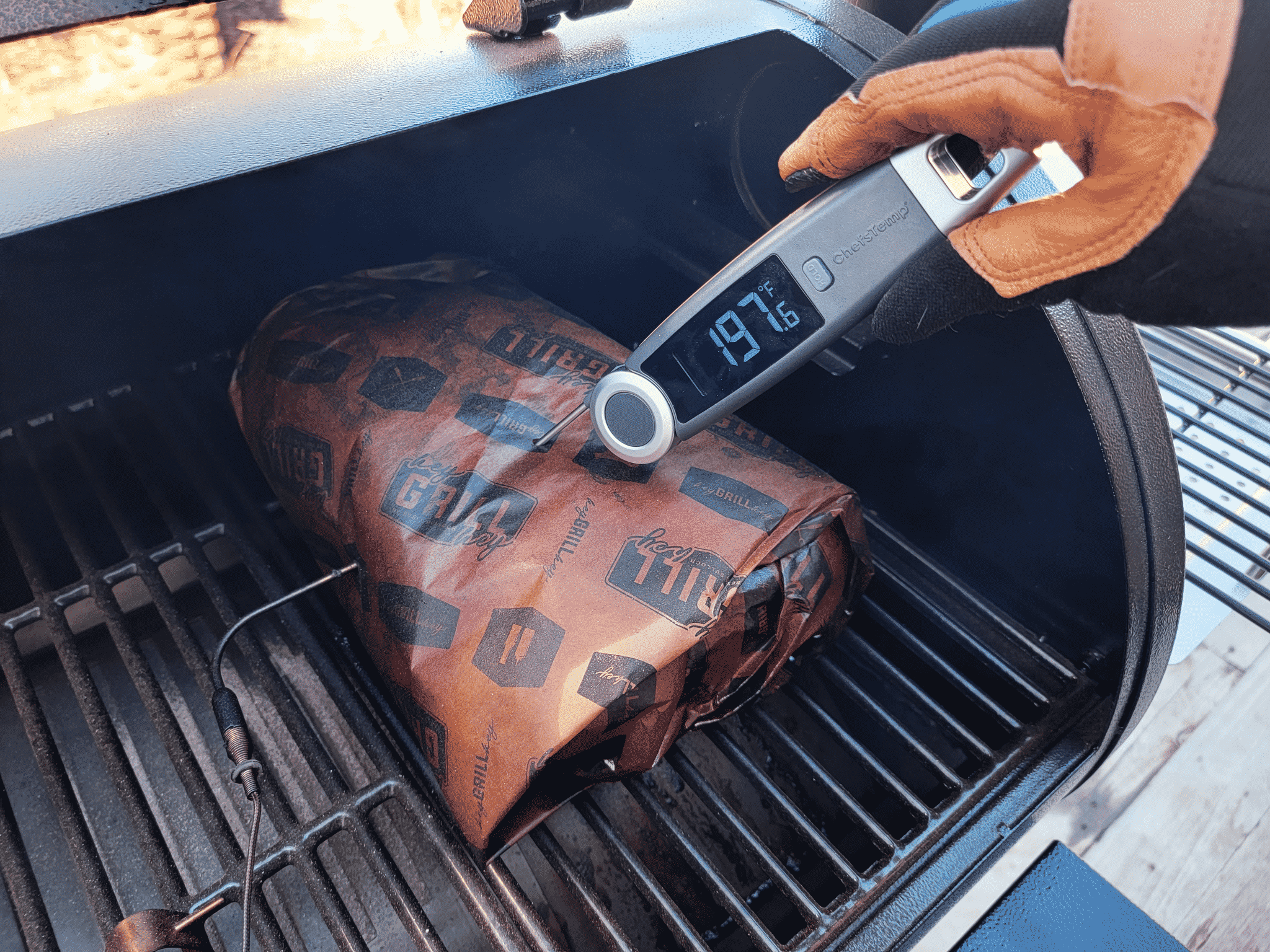 thermometer reading the temperature of meat on a grill