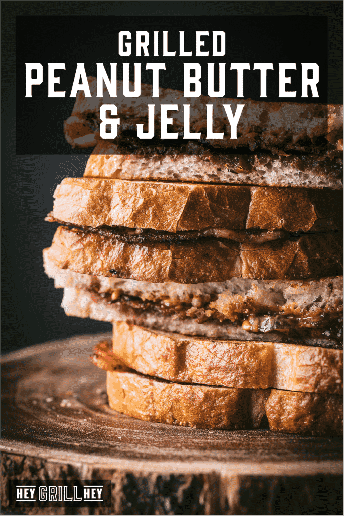Peanut butter and jelly sandwiches stacked on a wooden serving dish with text overlay - Grilled Peanut Butter and Jelly.