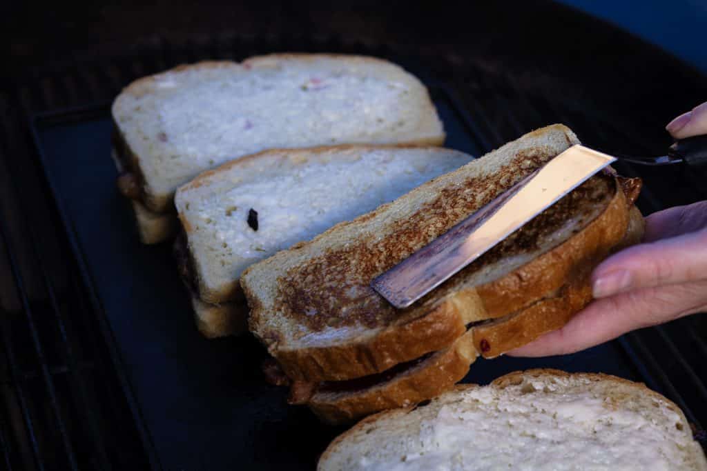Peanut butter and jelly sandwich being flipped on the grill.