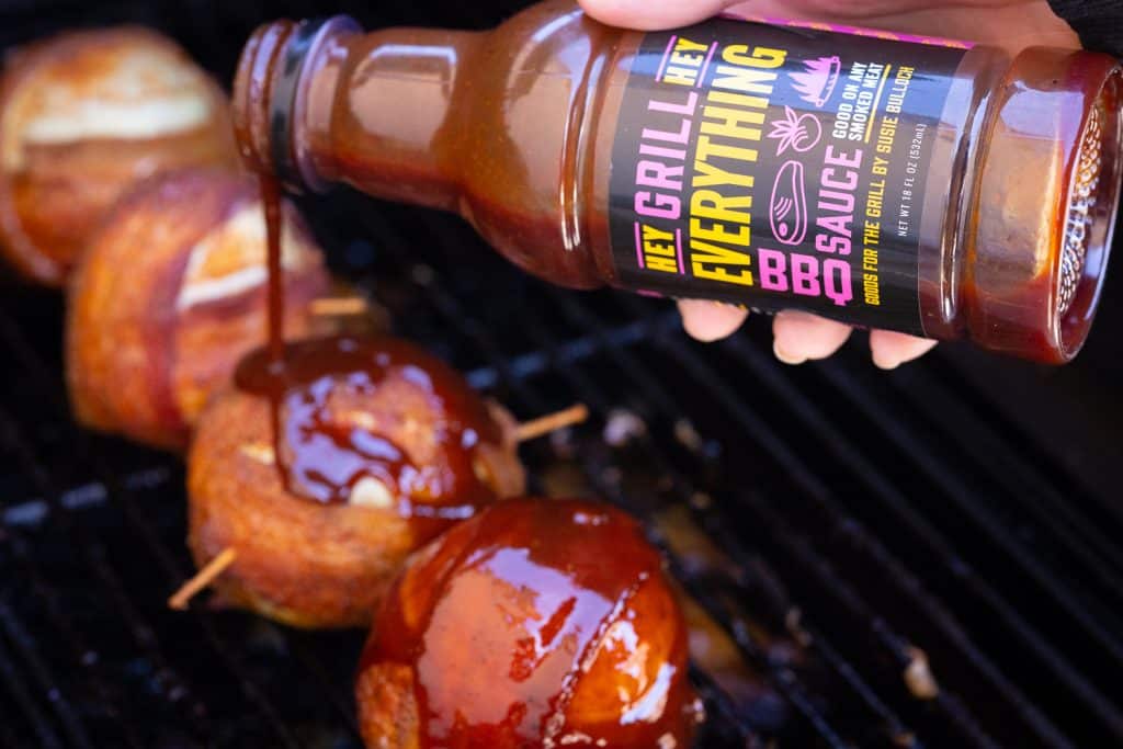 Hey Grill Hey Everything BBQ being poured over smoked onion bombs on the smoker.