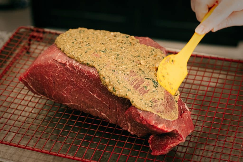 Herb butter being spread on a top round roast.