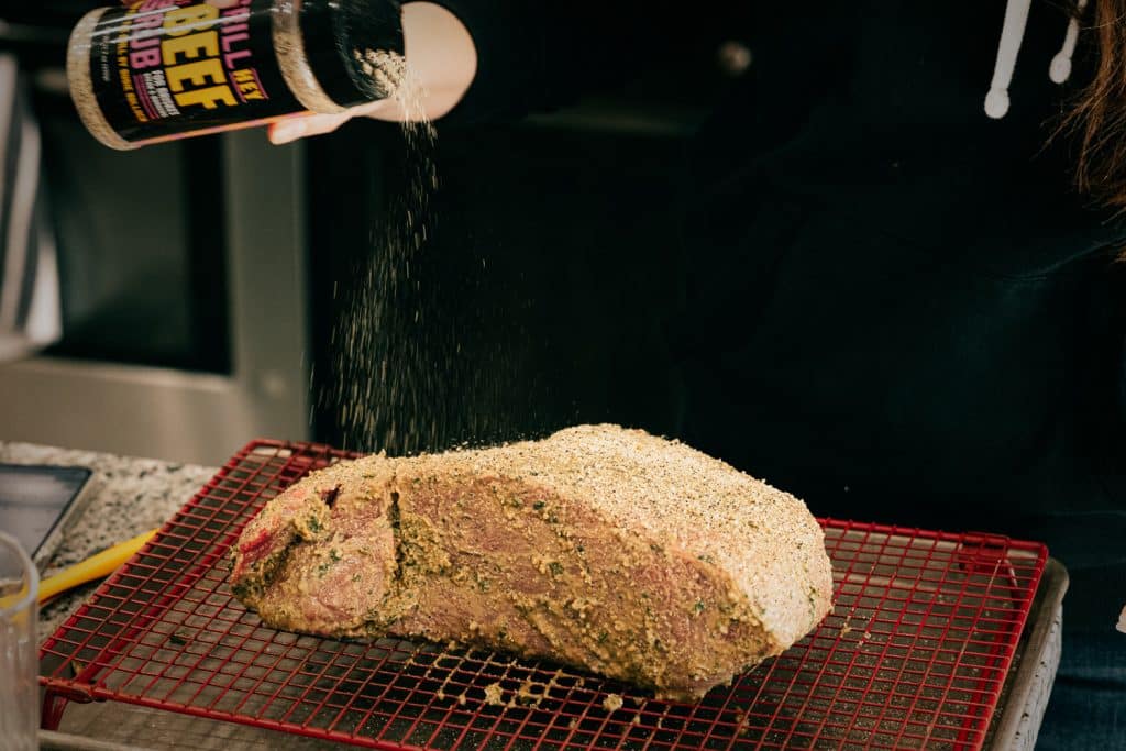 Hey Grill Hey Beef Rub being sprinkled on a buttered top round roast.