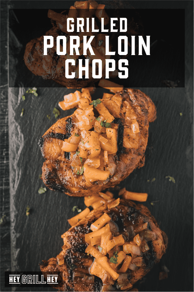 Three grilled pork loin chops topped with grilled apples and onions with text overlay - Grilled Pork Loin Chops.