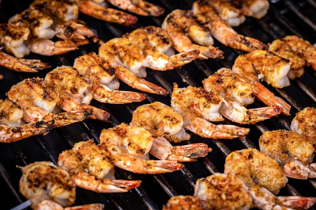 Blackened seasoned shrimp on skewers on the grill.