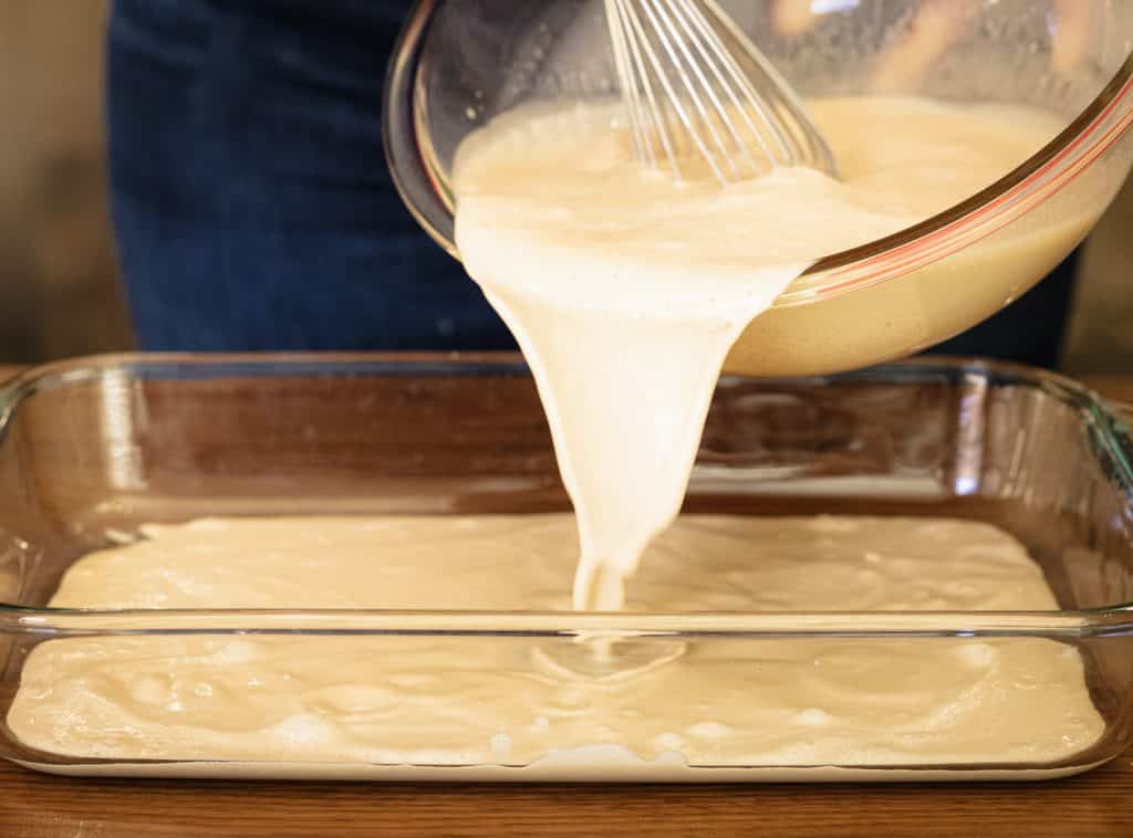Cream mixture being poured into a glass baking dish.