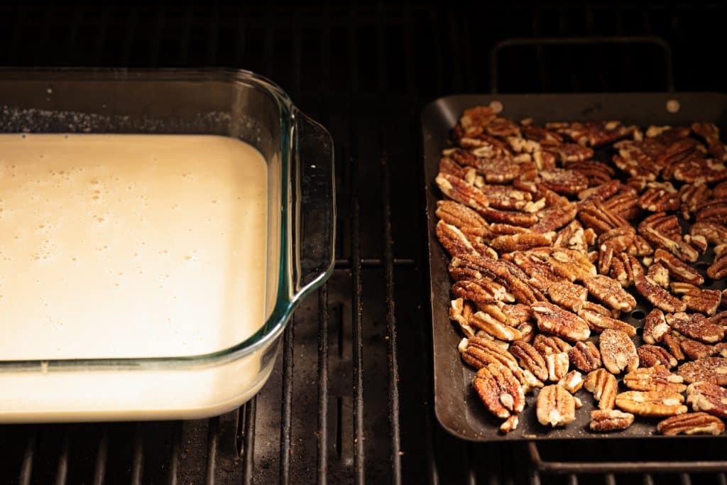 Ice cream batter in a dish next to pecans on the grill grates of a smoker.