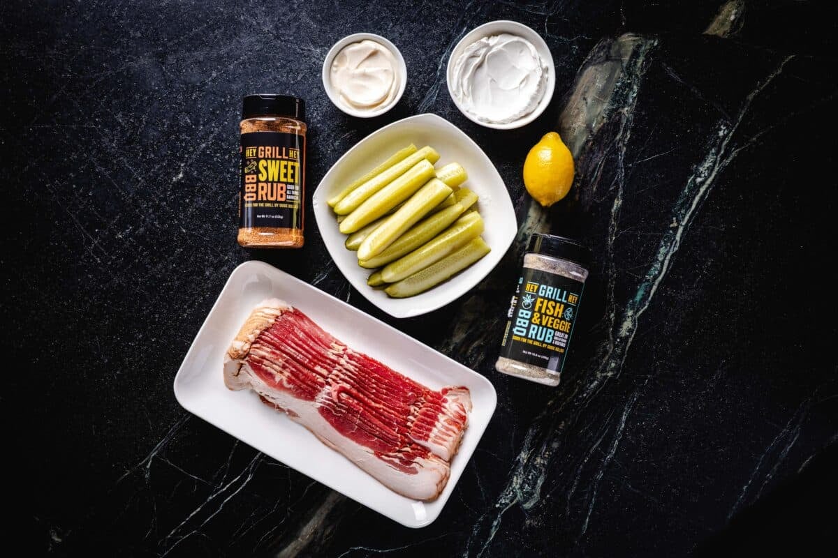 An overhead shot of pickle spears, Hey Grill Hey Fish & Veggie Rub, and other raw ingredients.