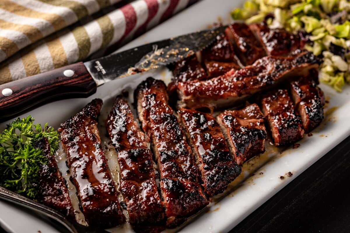 Sliced smoked pork steaks on a white plate.