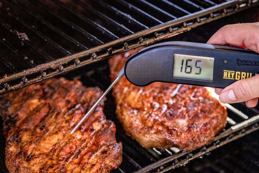 Pork steaks reading a temperature of 165 degrees F with an instant-read thermometer.