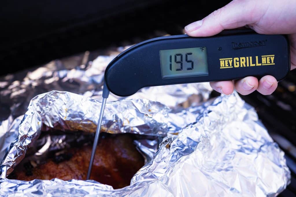 Meat thermometer reading 195 degrees F in a rack of ribs.