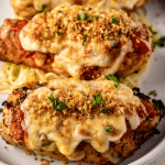 Grilled chicken parmesan topped with Panko on a white plate.
