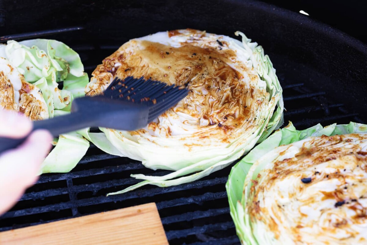 Cabbage on the grill being brushed with BBQ sauce.