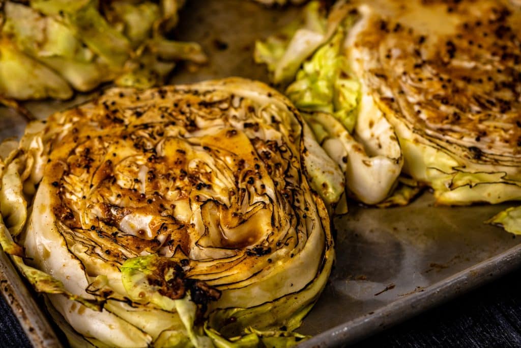 Grilled cabbage steaks on a baking dish.