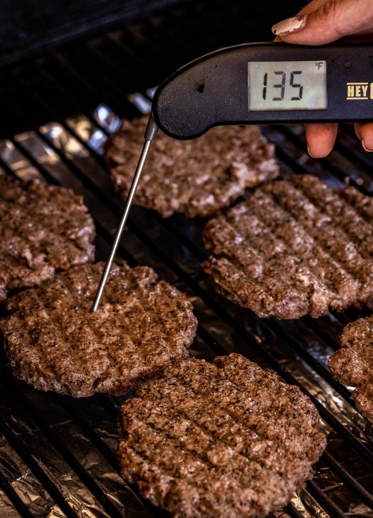 Brisket burgers on the smoker reading a temperature of 135 degrees F.