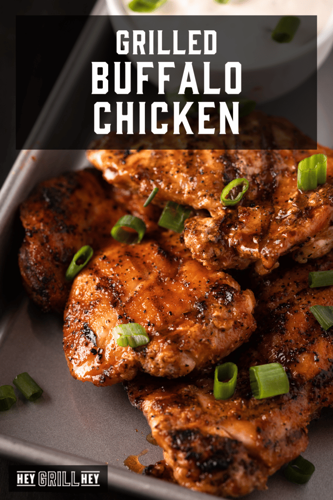 Grilled Buffalo chicken thighs on a baking dish with text overlay - Grilled Buffalo Chicken.