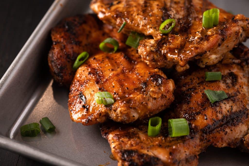 Grilled Buffalo chicken thighs on a baking dish.