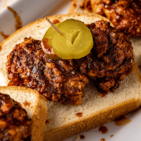 Grilled Nashville hot wings on a slice of bread topped with pickles.