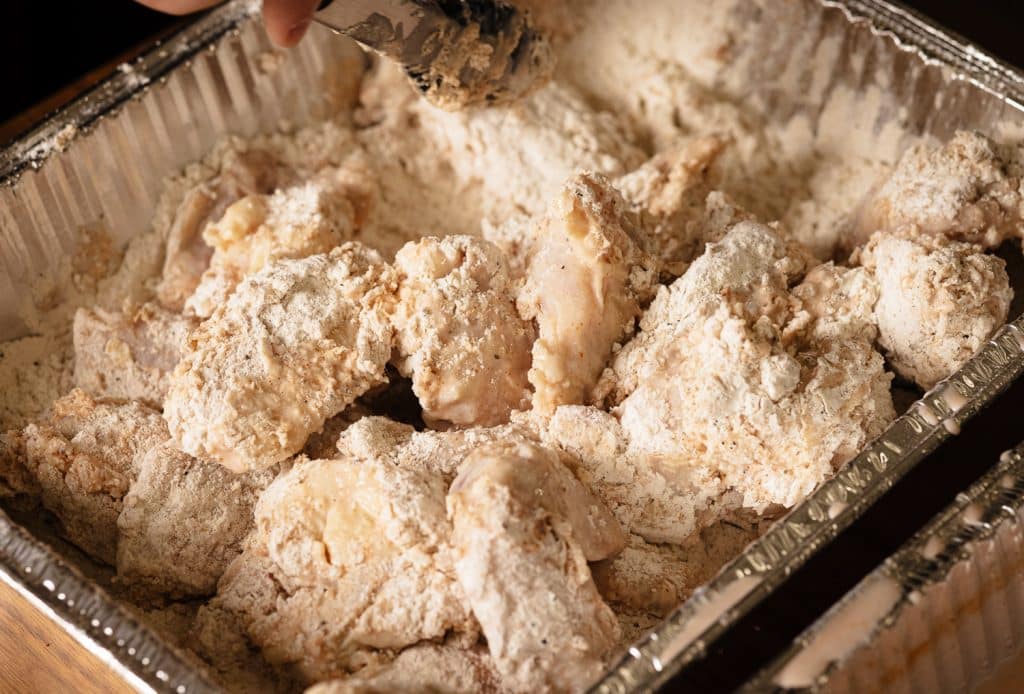 Chicken wings in a flour dredge.