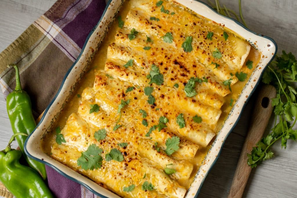 Smoked green chile chicken enchiladas in a large serving dish garnished with cilantro.